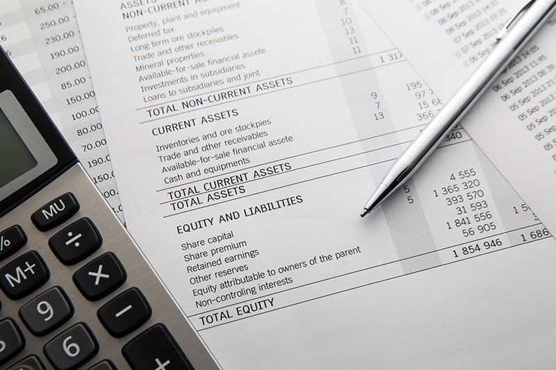 Pen and calculator kept on top of a balance sheet