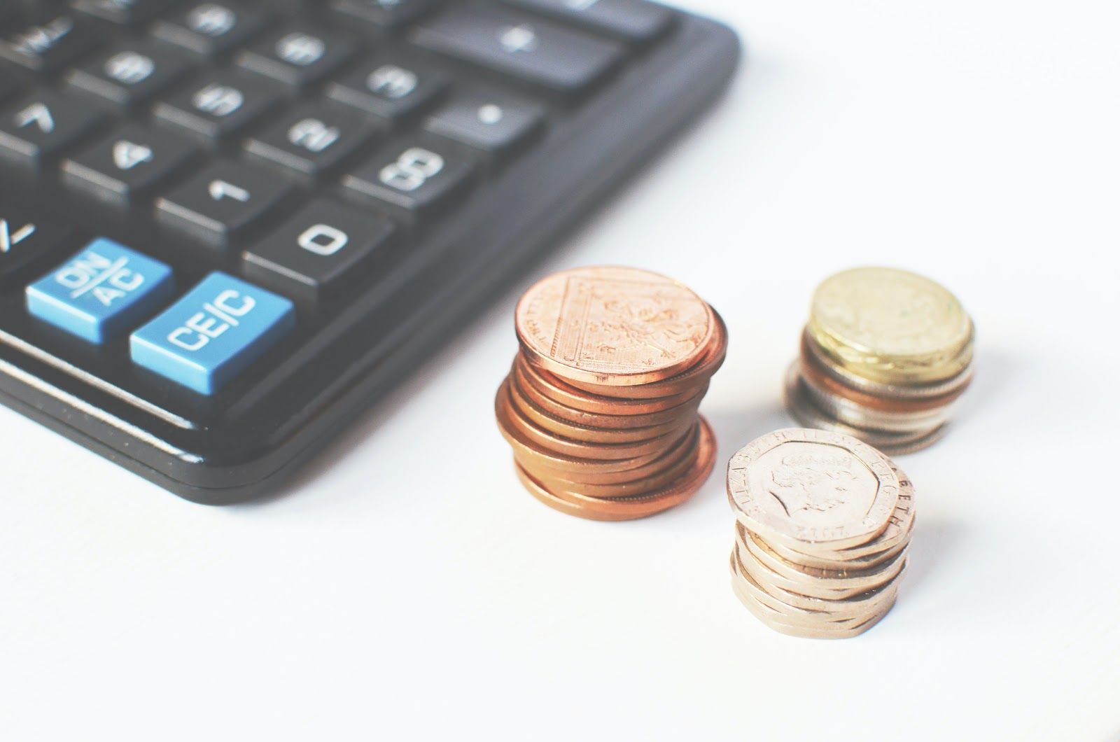 A calculator and stacks of different denominations of coins lying on the table