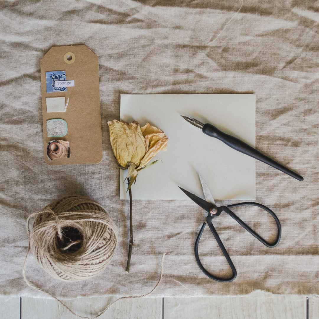 dried yellow rose, scissors, string, and a pen