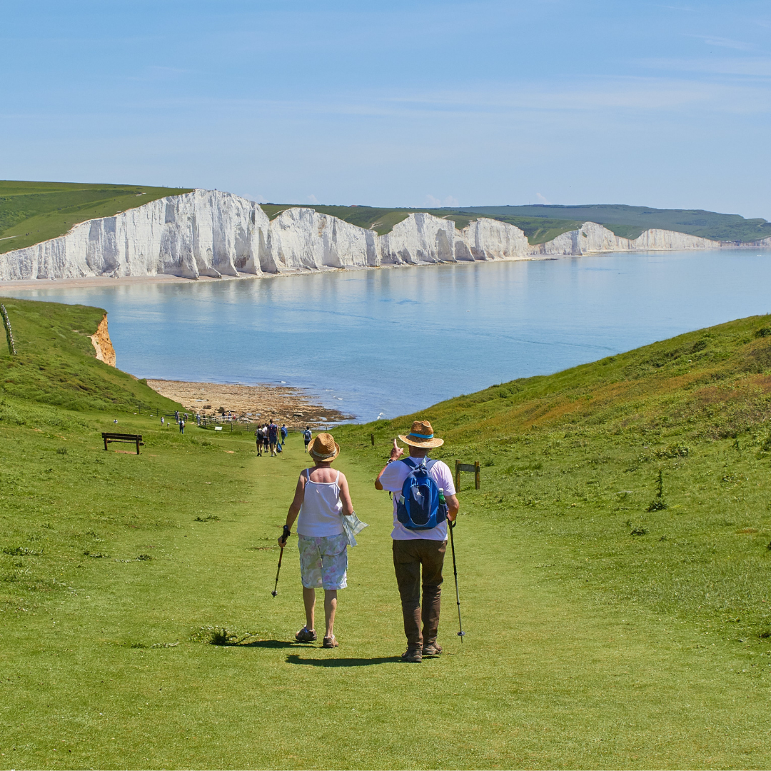 two senior citizens walking with sticks in hand