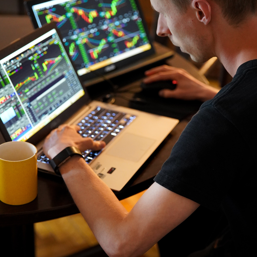 a man working on a laptop with stock market on screen