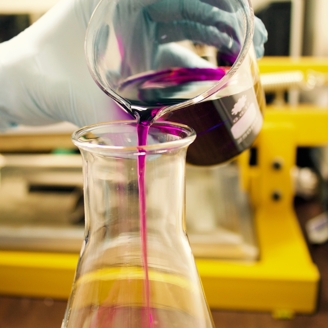 a purple colored liquid being poured in a beaker