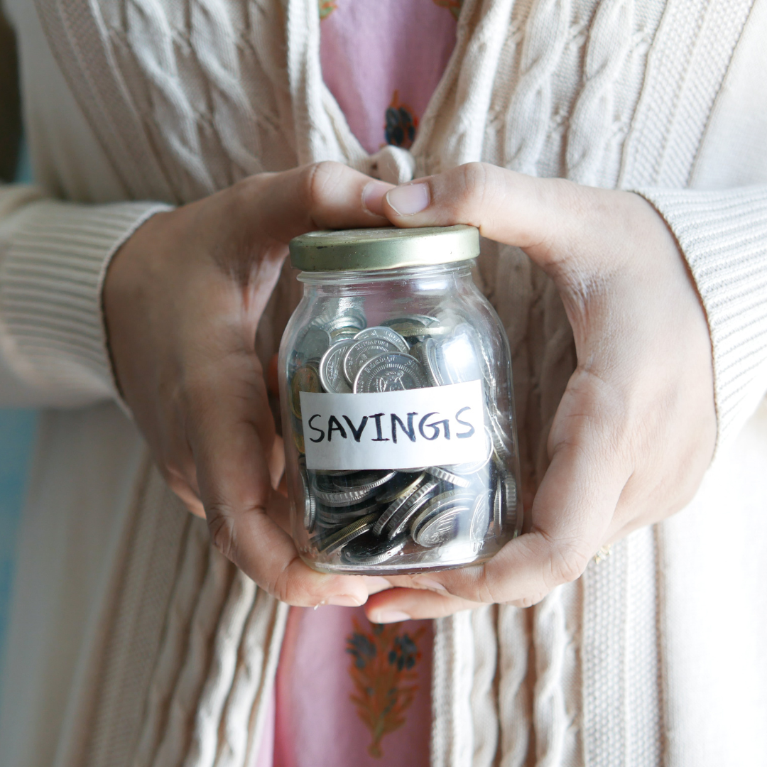 a woman holding a glass jar with coins in it