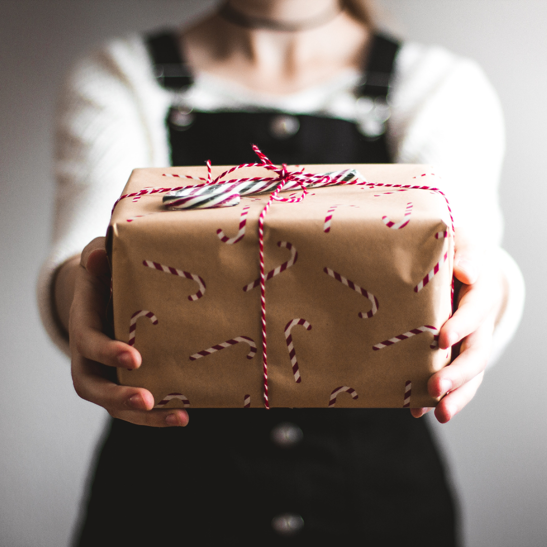 A lady handing over a gift-wrapped box